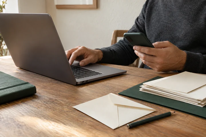A business owner handling correspondence with a laptop and phone